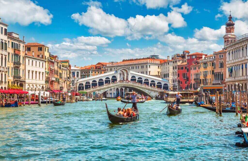 Gondeln auf dem Canal Grande vor der Rialtobrücke in Venedig, Italien, unter blauem Himmel. Perfektes Urlaubsziel.