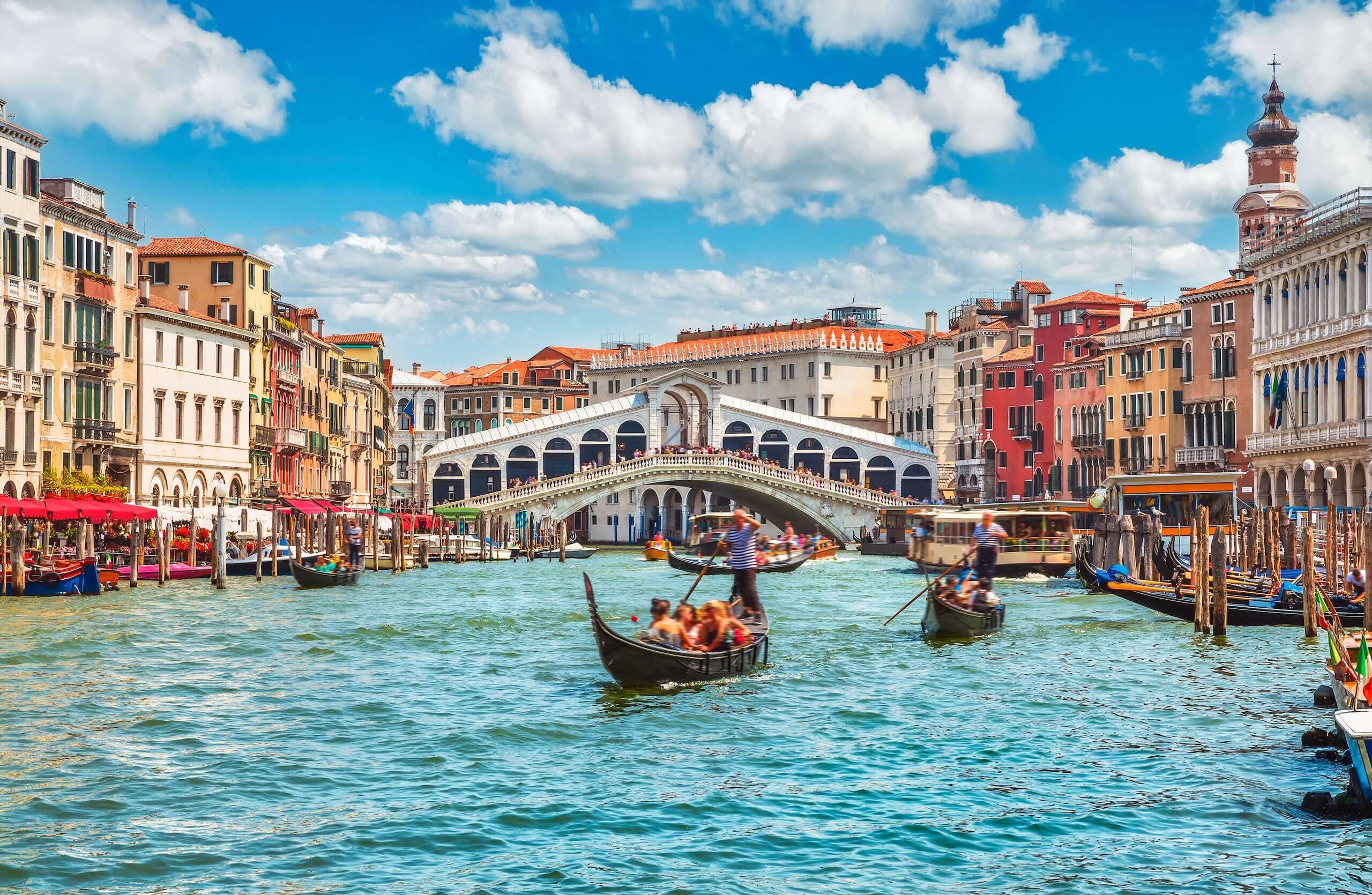 Gondeln auf dem Canal Grande vor der Rialtobrücke in Venedig, Italien, unter blauem Himmel. Perfektes Urlaubsziel.