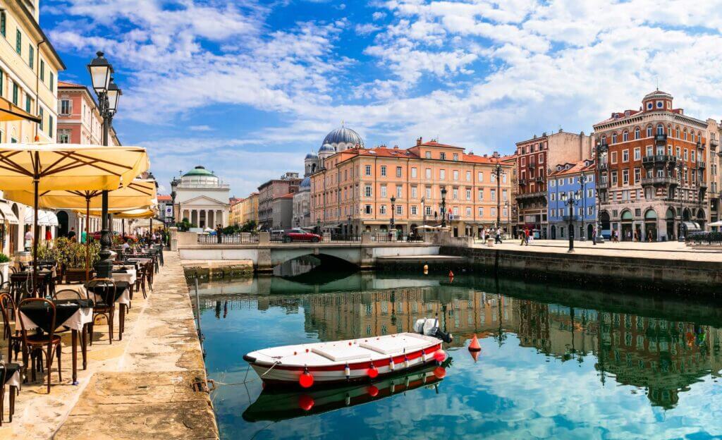 Historische Altstadt am Kanal mit Café-Terrassen, Boot und blauen Himmel – einladendes Reiseziel in Europa.