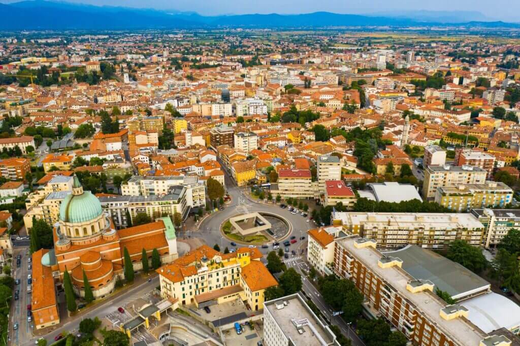 Luftaufnahme der Stadt Udine, Italien, mit historischer Architektur und charakteristischen orangefarbenen Dächern.