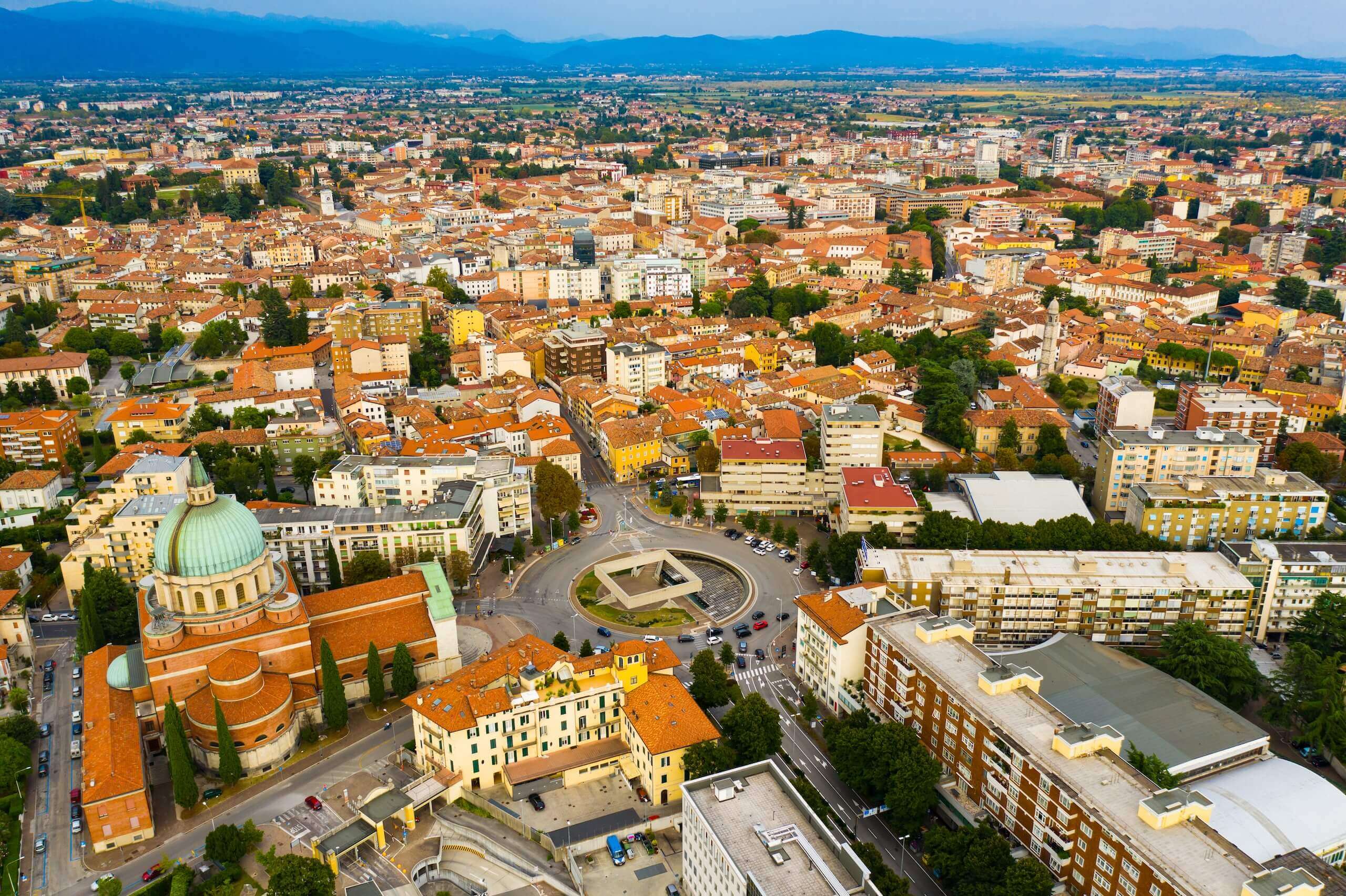 Luftaufnahme der Stadt Udine, Italien, mit historischer Architektur und charakteristischen orangefarbenen Dächern.
