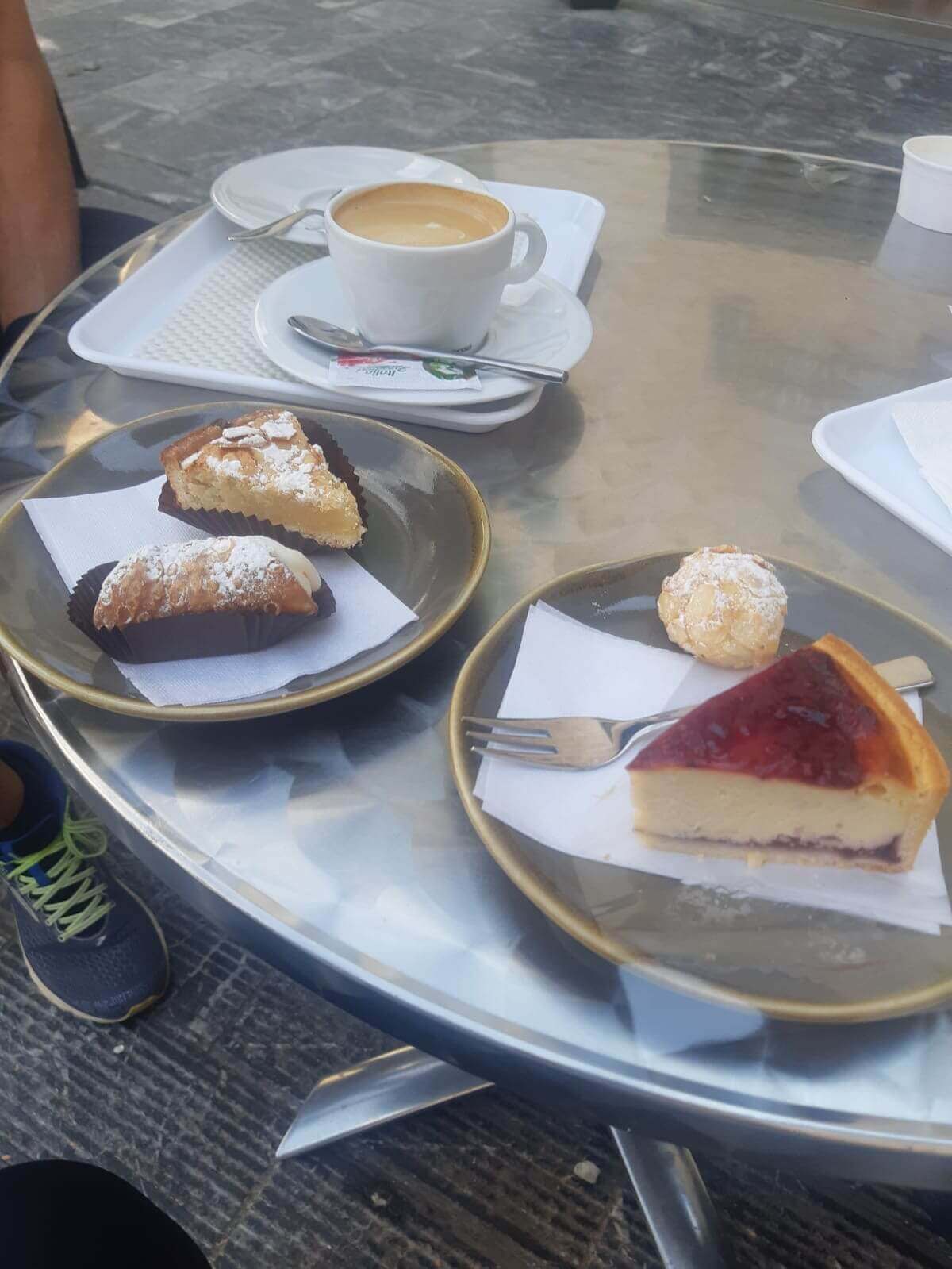 Kaffee und Kuchen mit Cannoli und Käsekuchen auf einem Tisch im Freien in einem Café.