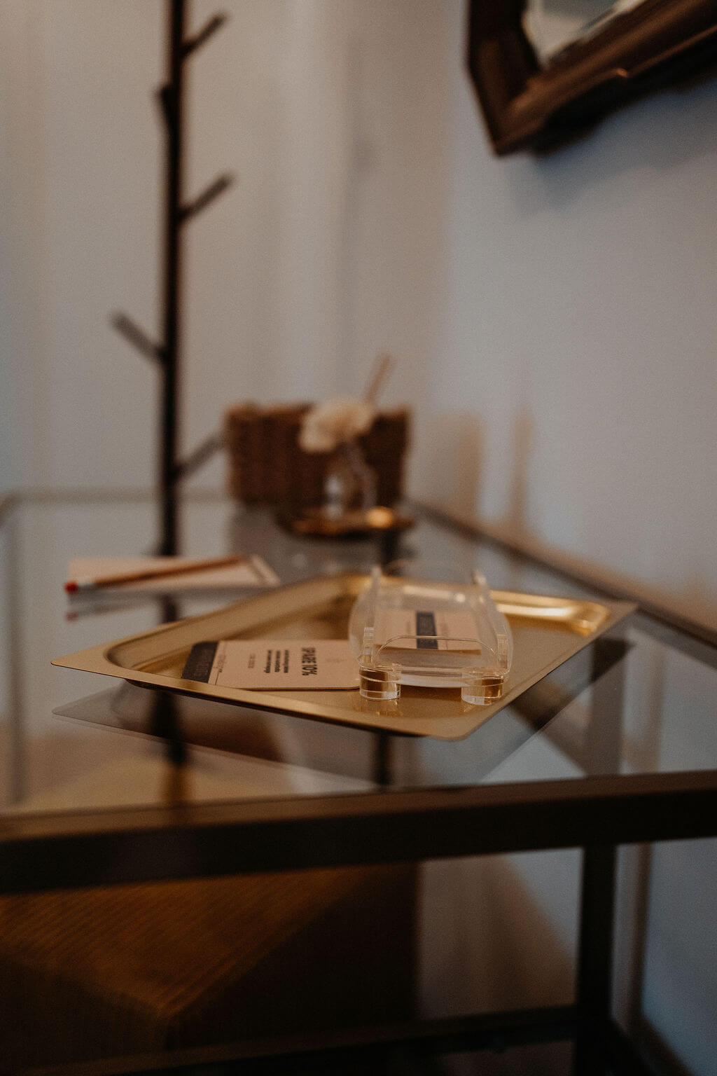 Modernes Interieur mit Glastisch, goldener Ablage und Stiftekorb für stilvolles Ambiente und Funktionalität.