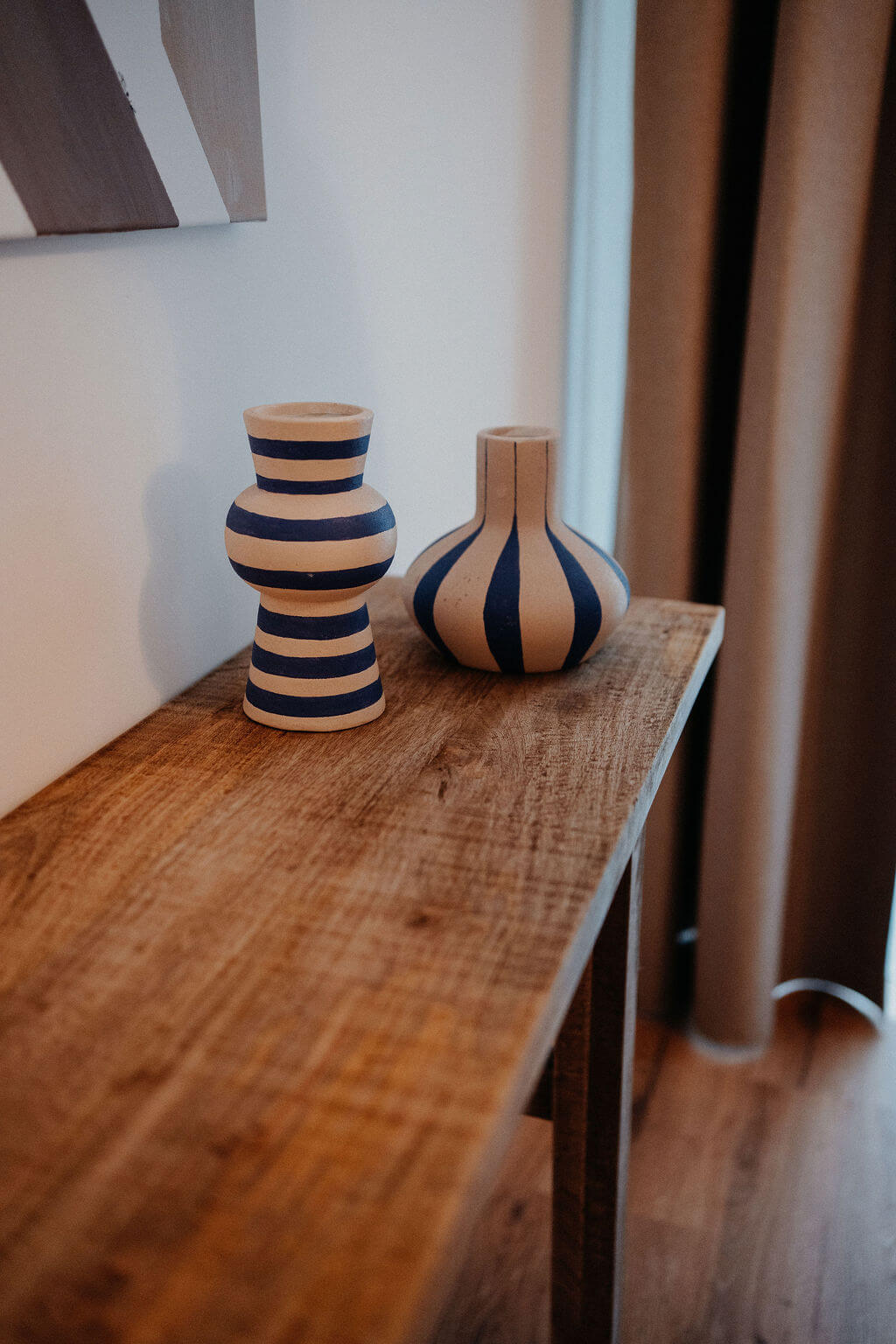 Zwei gestreifte Vasen auf einem Holztisch, minimalistisches Design in modernem Wohnambiente.