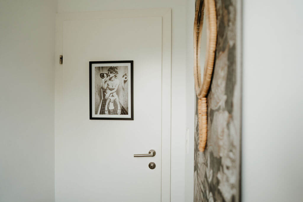 Minimalistisches Interieur mit gerahmtem Schwarz-Weiß-Foto an weißer Tür, harmonischer und moderner Raumgestaltung.