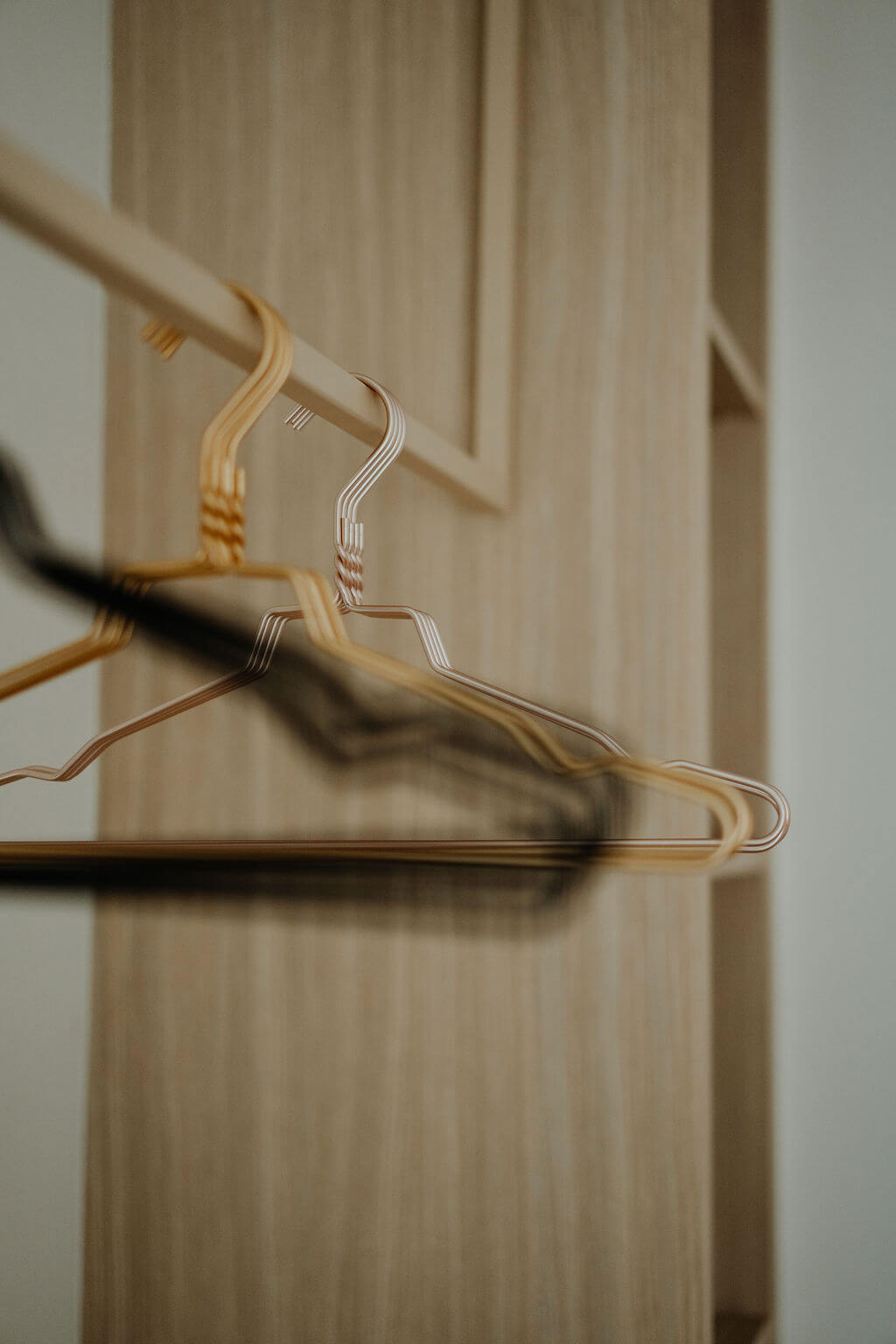 Leere Kleiderbügel, die an einer Holzstange im Kleiderschrank hängen. Minimalistisches Design, Ordnungskonzept.
