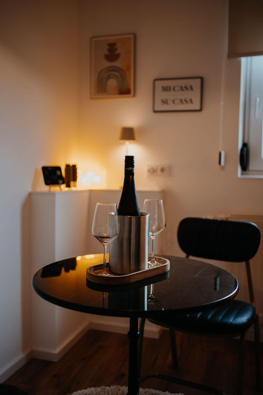 Eleganter Tisch mit Weinflasche und Gläsern im stilvollen Interieur, perfekt für eine gemütliche Abendatmosphäre.