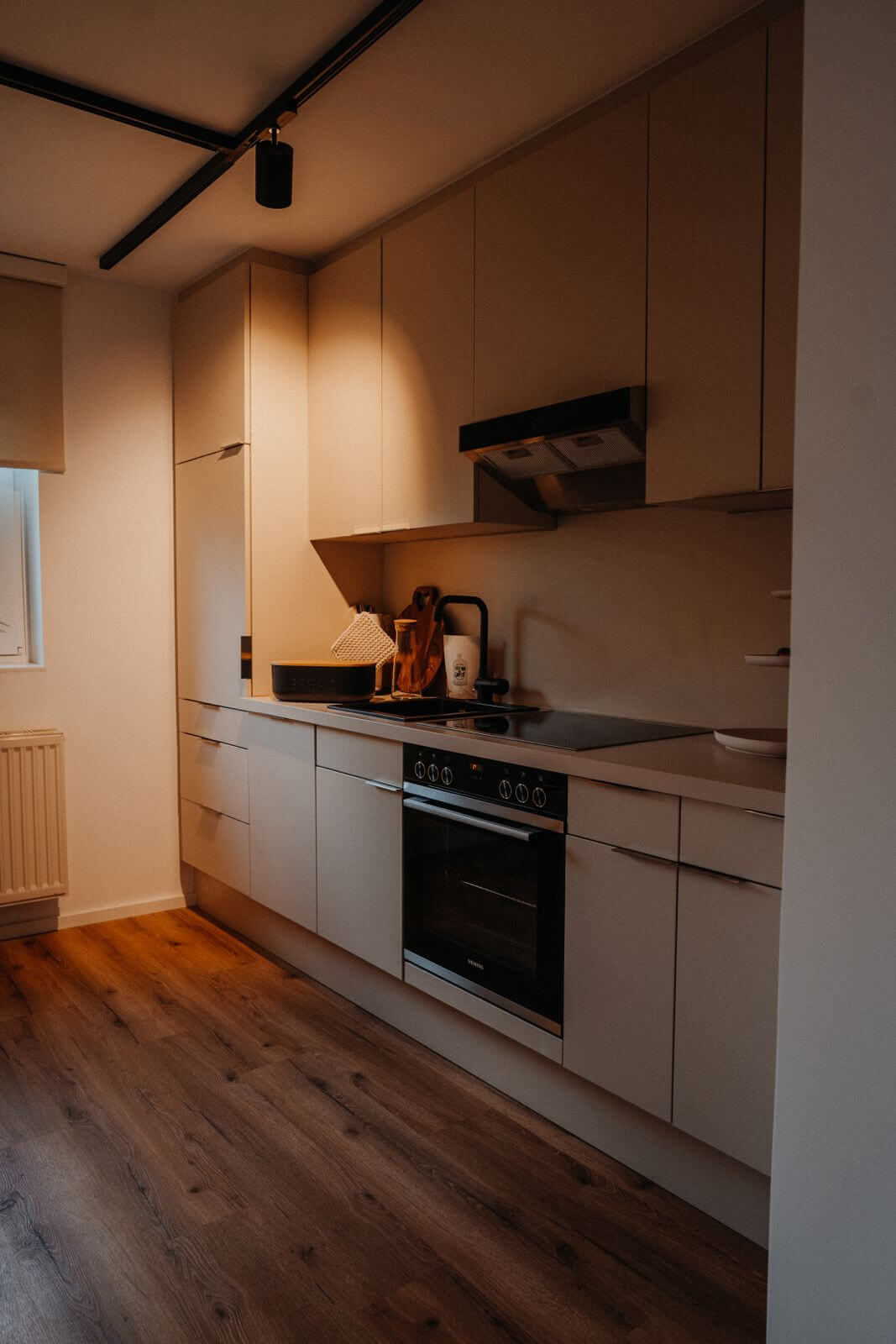 Moderne Küche mit Holzfußboden, weißen Schränken und Elektroherd für stilvolles Kochen und Wohnen.