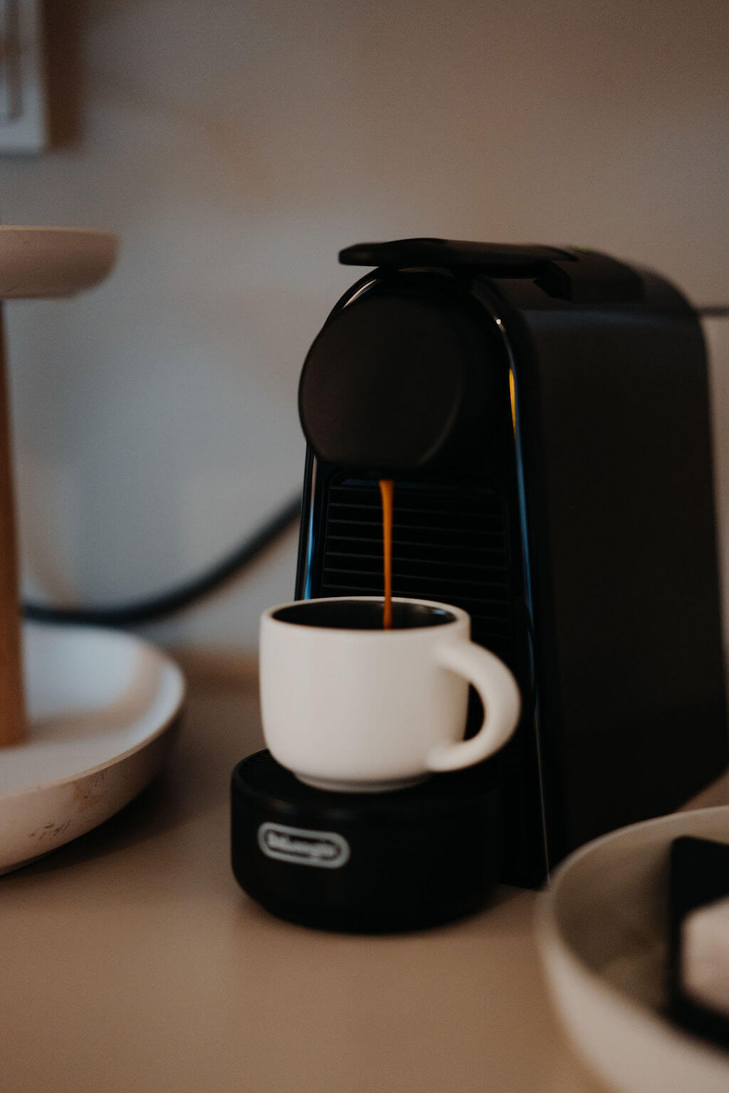 Espressomaschine brüht frischen Kaffee in weiße Tasse auf Küchenarbeitsplatte. Perfekter Start in den Tag!