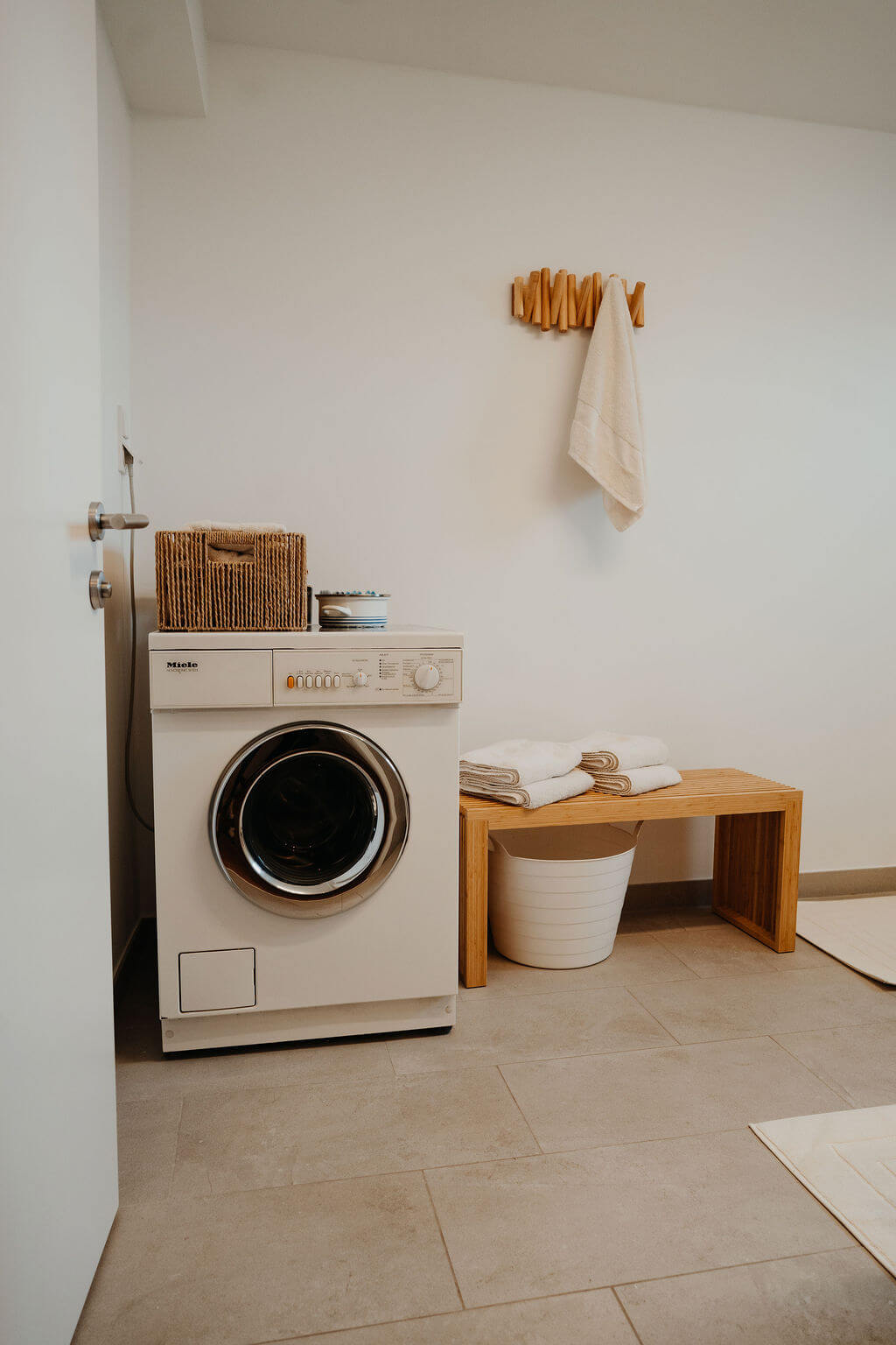 Moderner Hauswirtschaftsraum mit Waschmaschine, Handtüchern und Holzmöbeln für stilvolle Organisation.