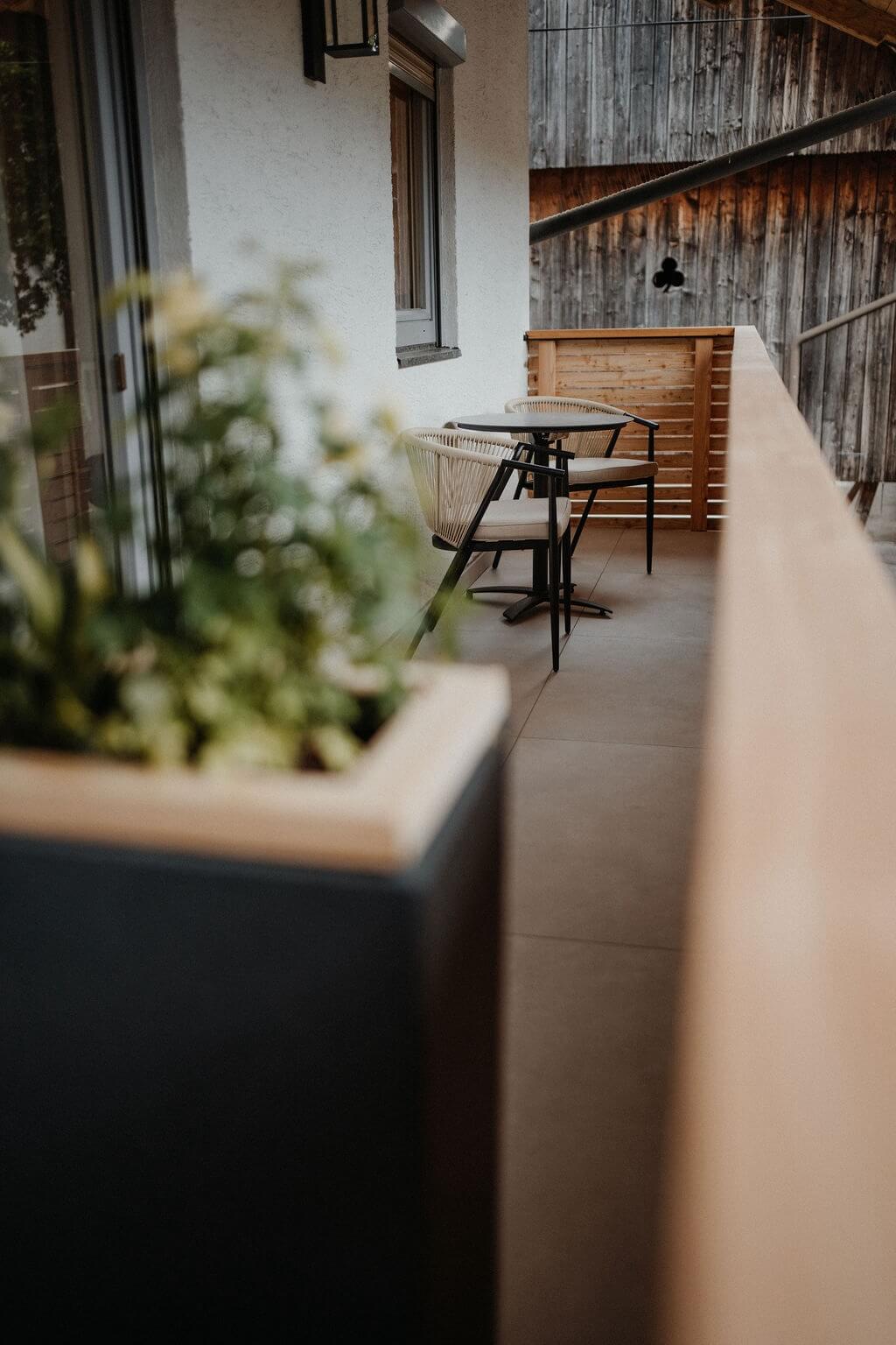 Gemütlicher Balkon mit Tisch und Stühlen, neben Pflanzen, ideal für entspannte Momente im Freien.