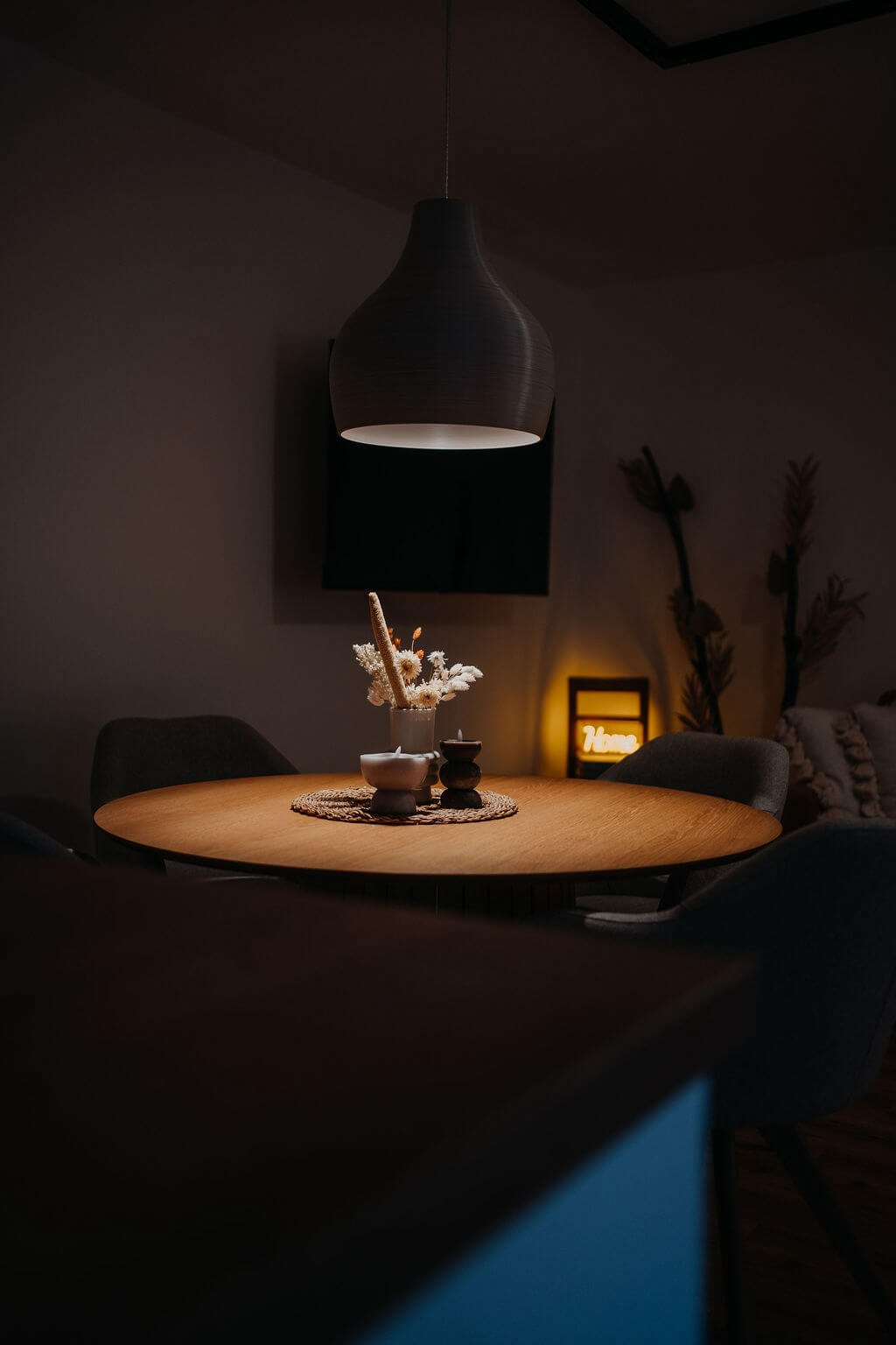 Gemütlicher Essbereich mit rundem Holztisch, modernem Leuchter und Dekoration für stimmungsvolle Beleuchtung.