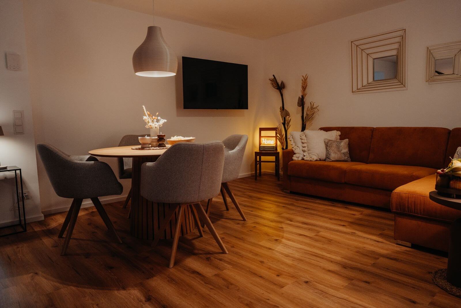 Gemütliches Wohnzimmer mit Holzboden, stilvollem Esstisch, grauen Stühlen und braunem Sofa, moderne Dekoration.